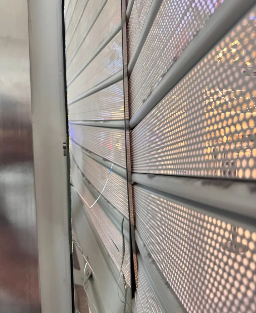 Persiana de lama microperforada vista desde dentro, con la luz de la calle pasando por los agujeros
